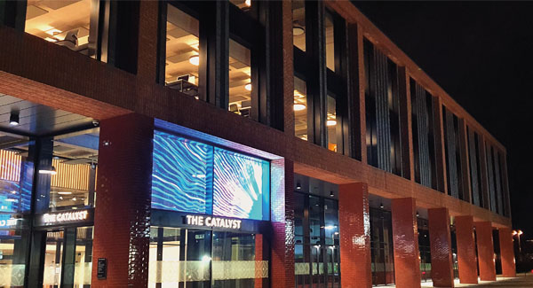 The exterior of the Catalyst building lit up at night time