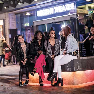 A group of females sitting and talking outside the Regent Theatre in Hanley