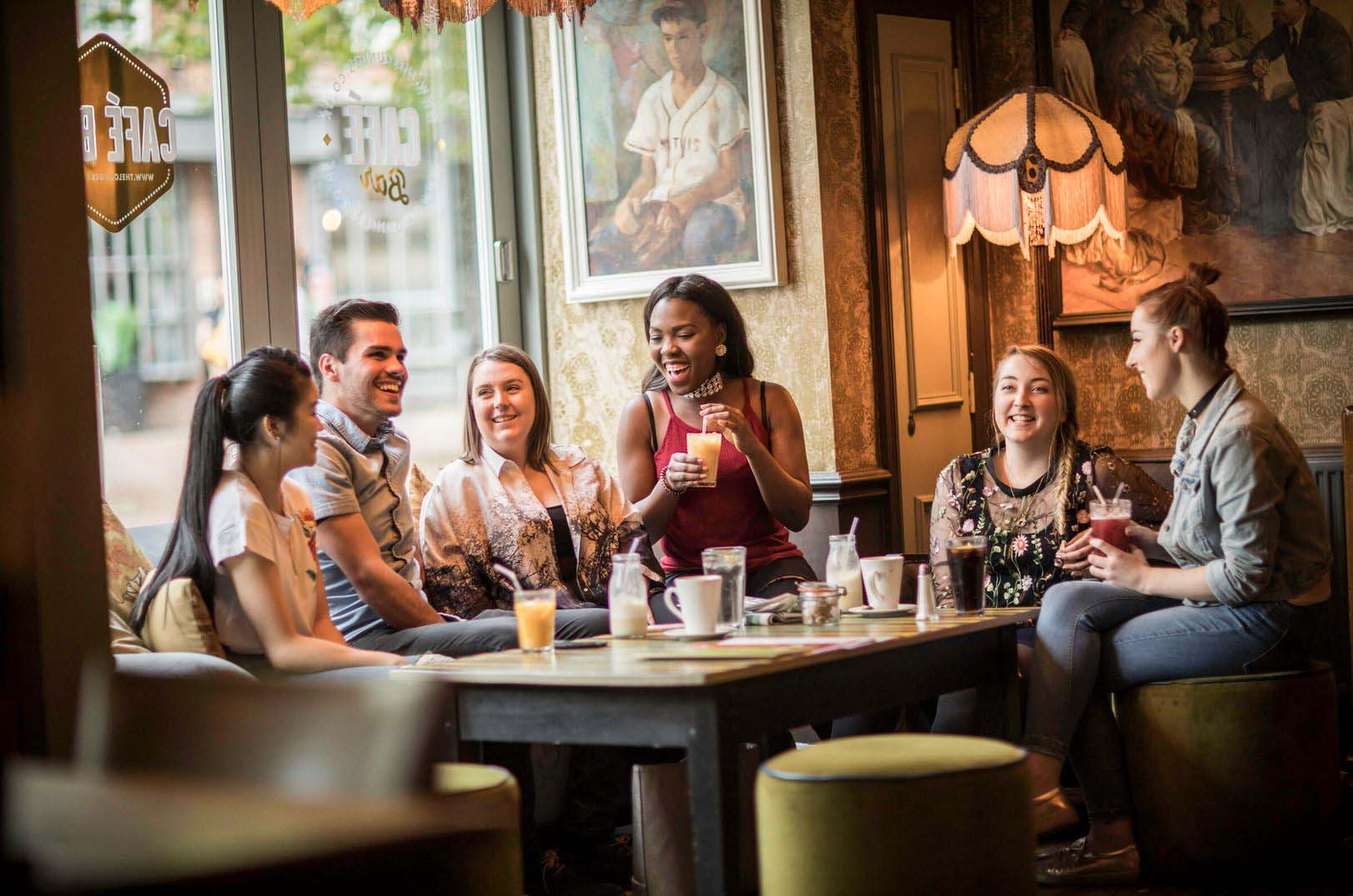 A group of six students sitting in a lounge chatting with a selection of beverages