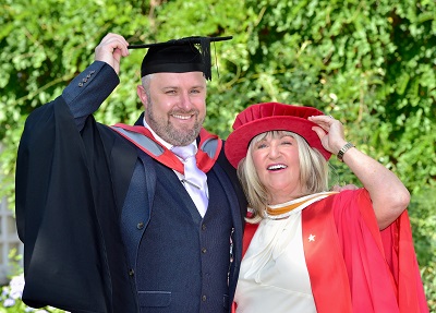 Man and woman in graduation dress outdoors