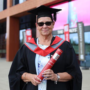 Annette Walklate in graduation gown and cap holding a scroll