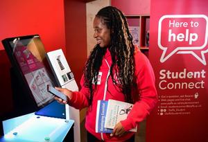 Female student holding books and mobile phone and looking at screen