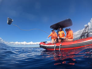 Professor Claire Gwinnett throwing a sampling bucket of the side of a boat on the sea