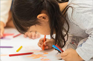 A child drawing a picture with colourful crayons