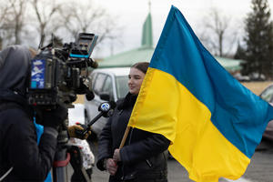 A television crew interviewing a women holding the Ukraine flag