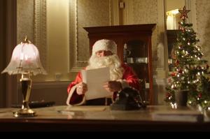 Santa sat at a desk reading a child's letter