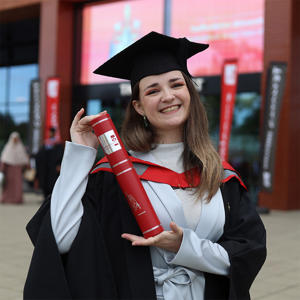 Eleri Turner in her graduation cap and gown holding a scroll