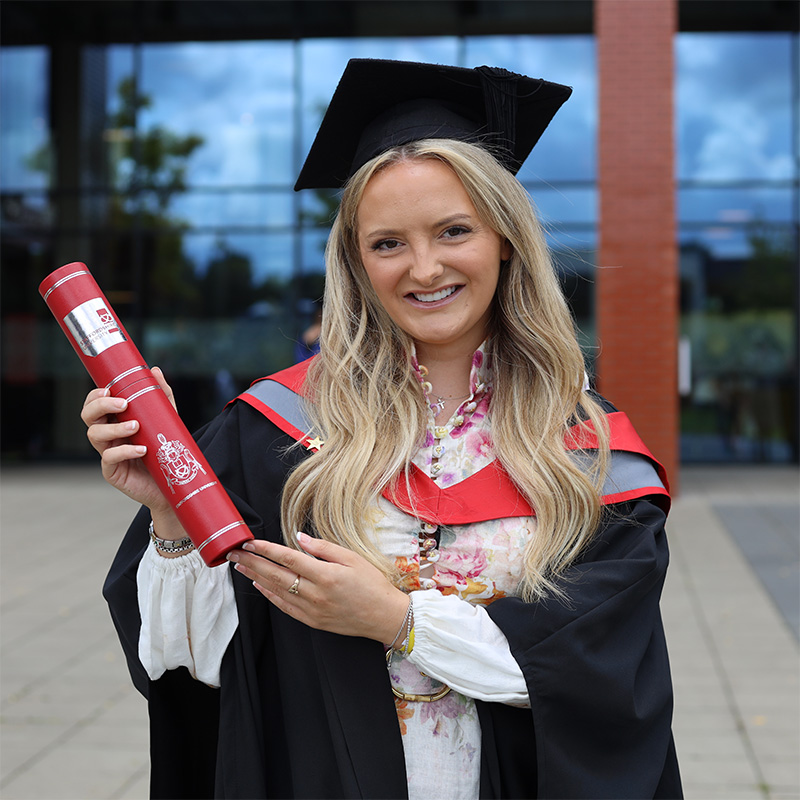 Gabrielle Rushton in her graduation cap and gown holding a scroll