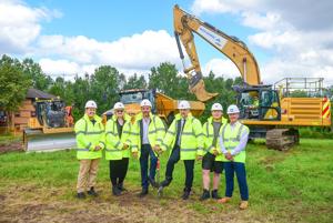 Six people in high vis and hardhats in field with heavy machinery