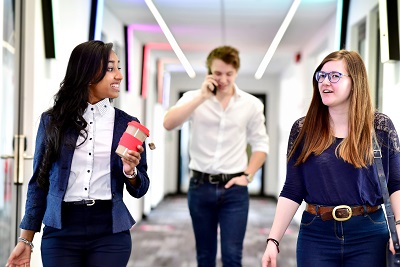 Three smartly dressed young people walking and talking