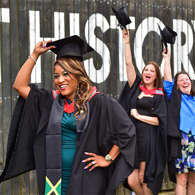 Kerry Ann Hemans in her graduation gown holding her cap in the air