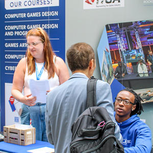 A female and male engaging with prospective students at a recruitment fair.