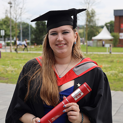 Libby Bourne in her graduation cap and gown holding a scroll