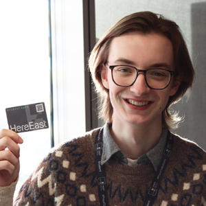 A male student holding a Here East discount card.