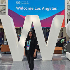 A female lecturer poses with AWS logo at AI summit in Los Angeles, California.