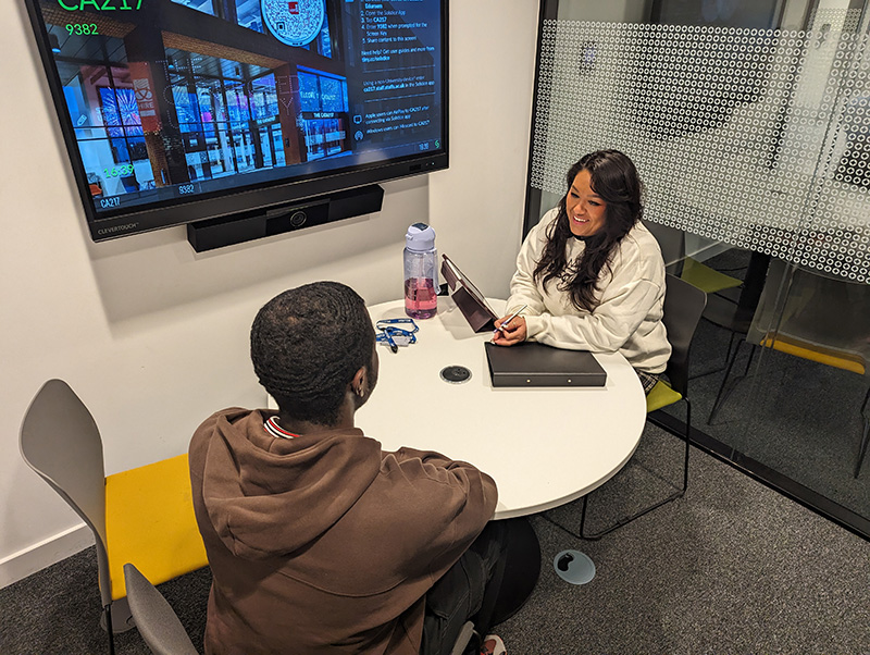 A student being interviewed at a table by a woman