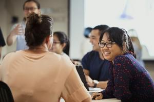 four people sitting and one standing in a classroom environment.