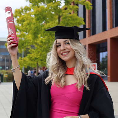 Teresa Sinaguglia wearing a graduation cap and gown, holding a scroll