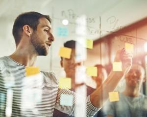 Group of people working with post-it notes photographed through glass wall.