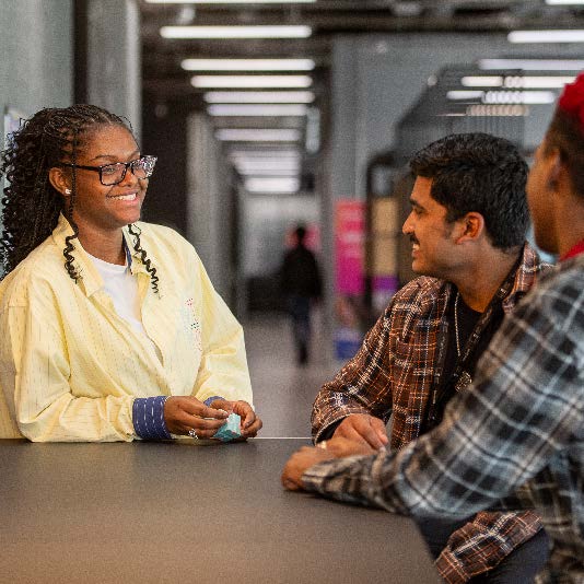 Female student smiling at two male students