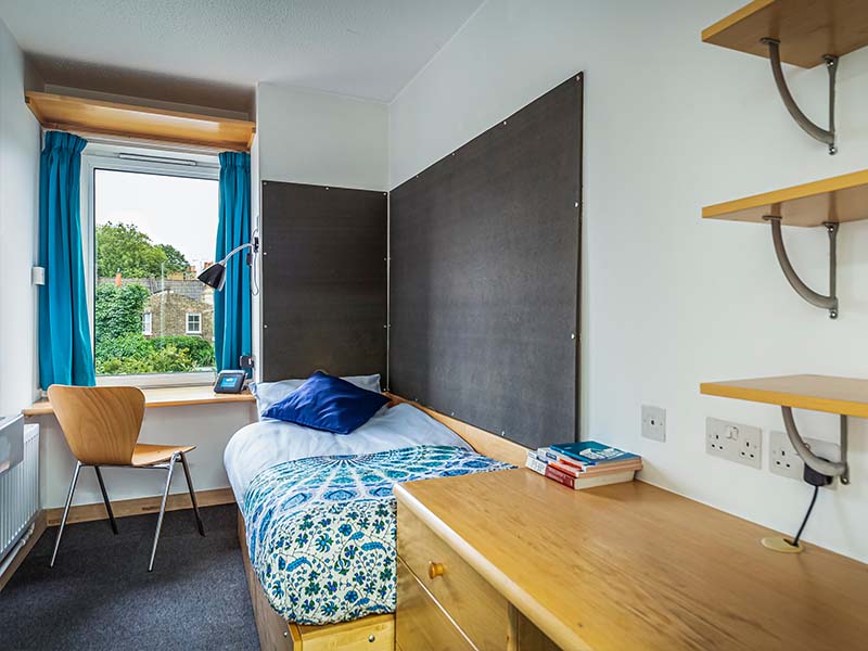 Well Street bedroom featuring a bed, desk, chair, drawers, shelving and pin board