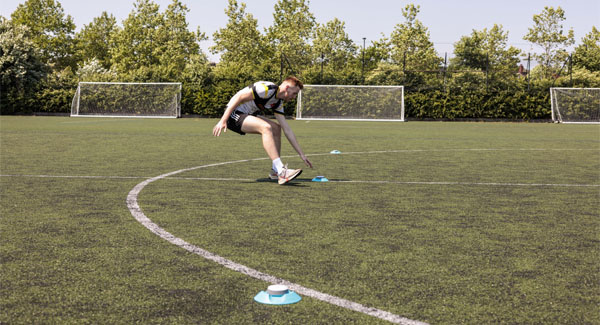 A male sports student wearing active clothing is training on the football pitch