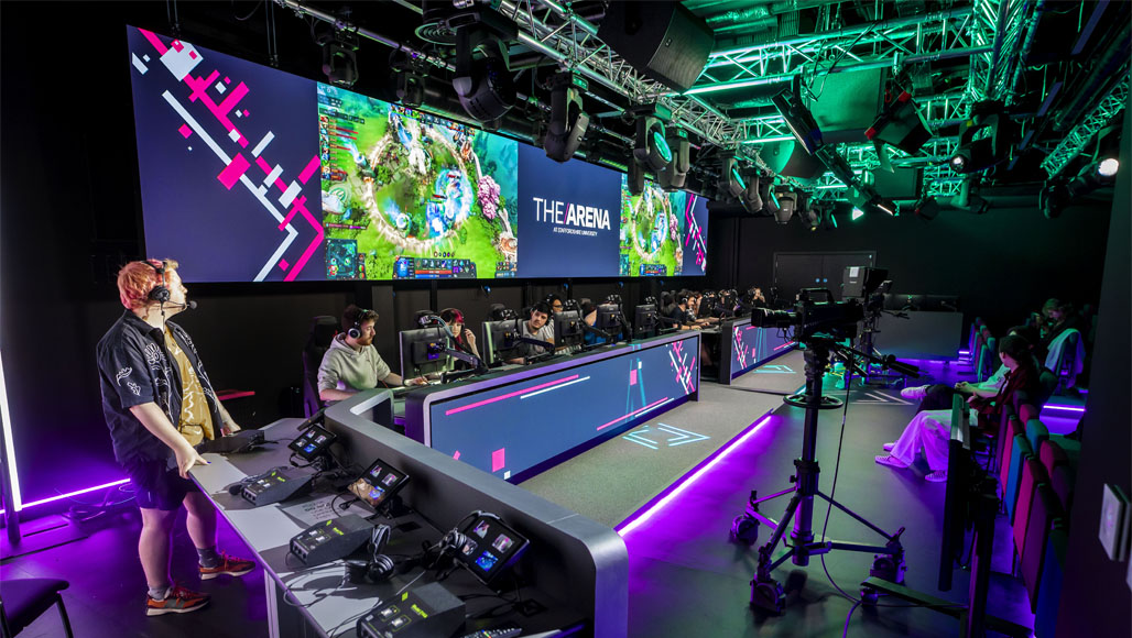 Students are streaming video games to an audience in the ambiently lit Esports arena