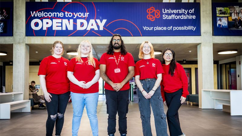 Five student ambassadors wearing red tshirts are standing in the Catalyst posing for a photo