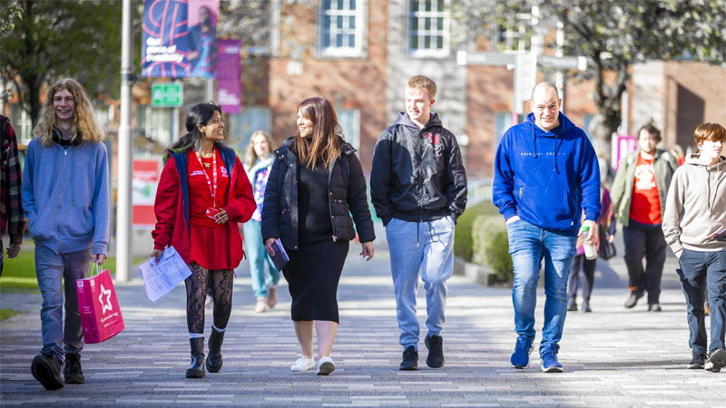 A group of open day visitors are taking a walking tour with a student ambassador on College Road