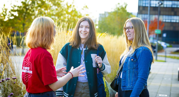 A student ambassador is chatting outside to visitors during an open day at Leek Road campus